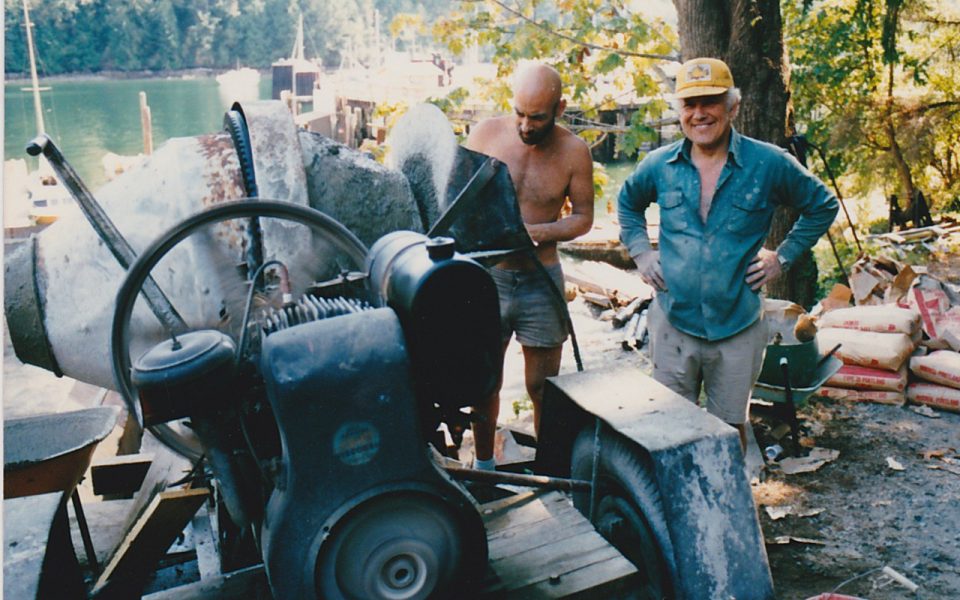 Two men in front of a cement mixer