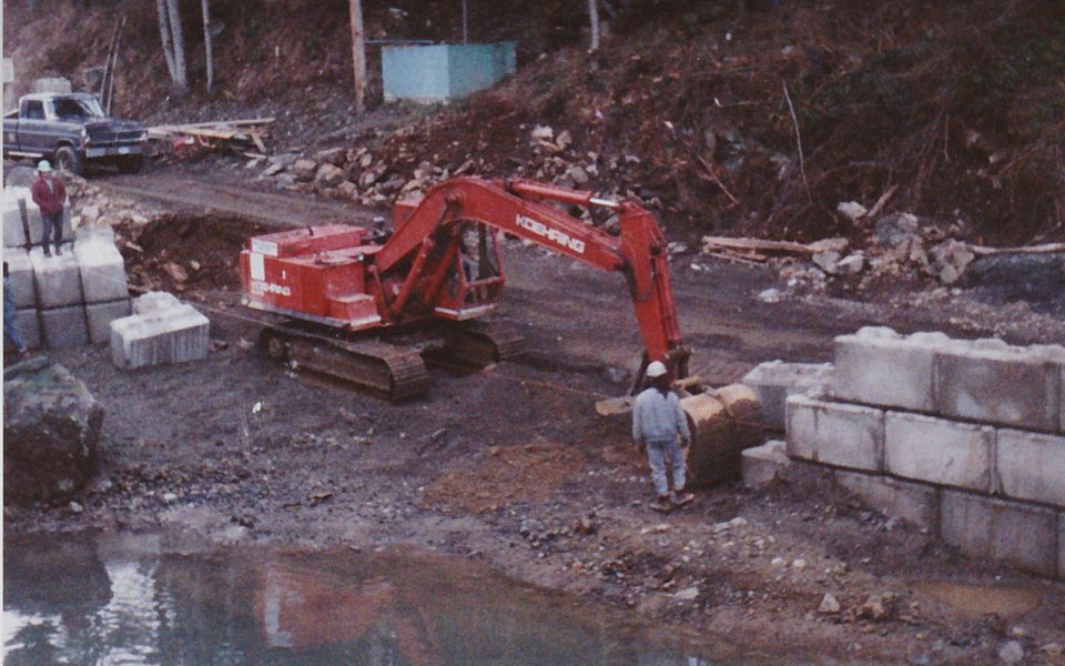 Man watching excavator placing concrete blocks