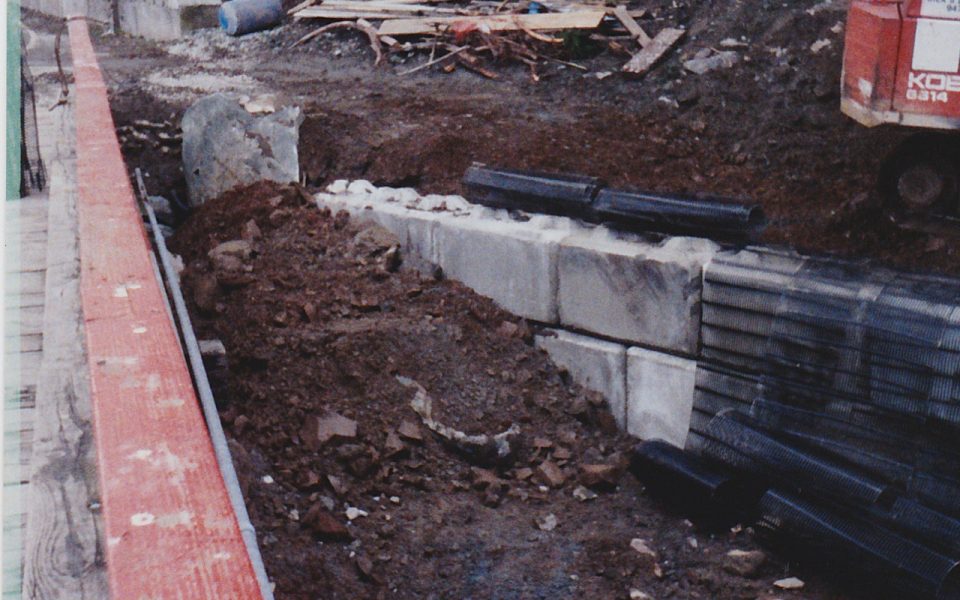Concrete block wall being buried with soil