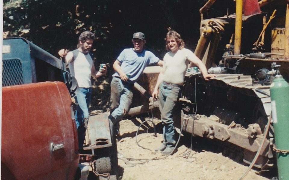 Three men standing beside excavator