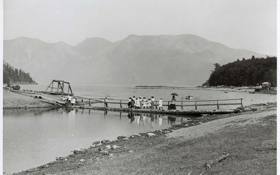 Black and white photo of old bridge across a lagoon with people walking on it