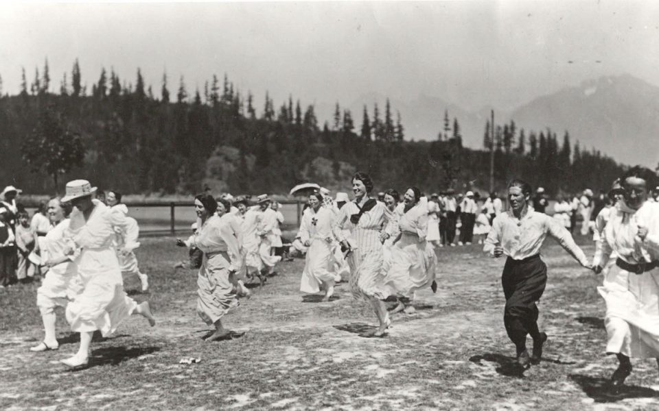 Black and white photo of men and women running in a field